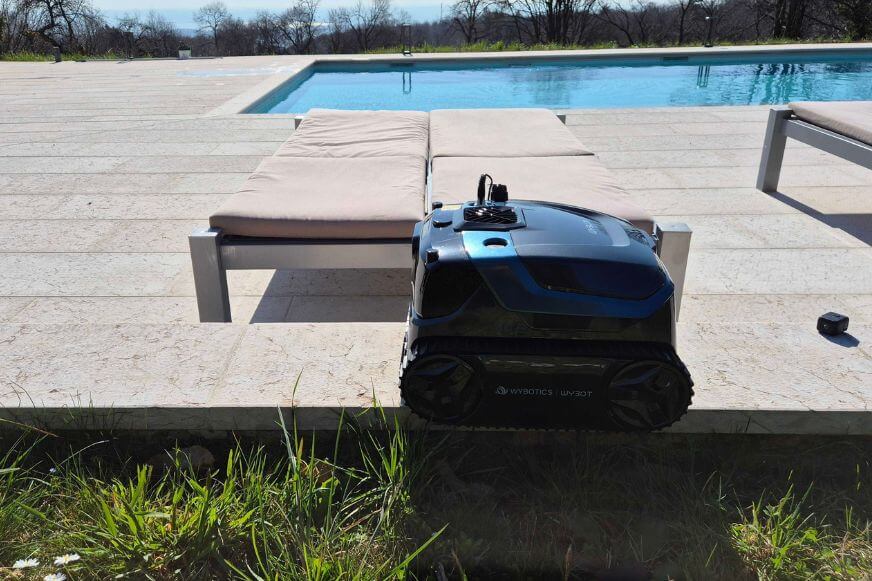 WYBOT S3 Poolroboter steht auf einer Poolterrasse mit Liegen und Panoramablick. Netzwelt First Look Event.